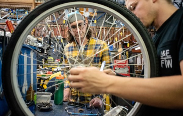 Two volunteers work on repairing a bike wheel